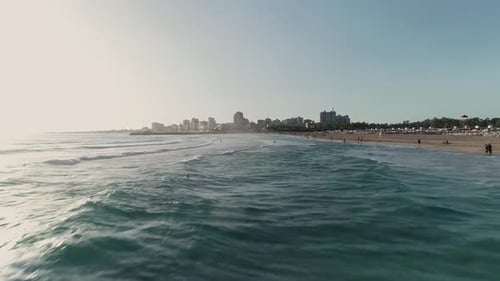 Low aerial view of tourists near a beach enjoying their vacation in the beach, ocean waves and sun i