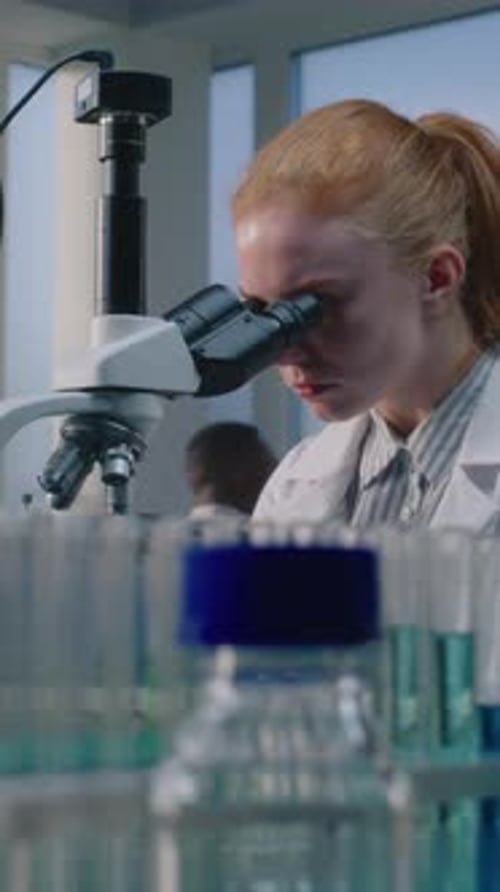 Woman Scientist Working with Microscope in Laboratory