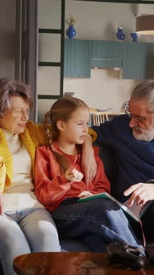Grandparents Reading a Book with Granddaughter at Home