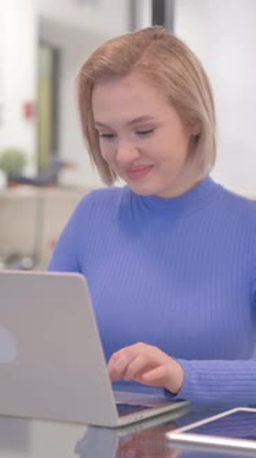Young Woman Smiling at Camera while Working on Laptop in Office, vertical video