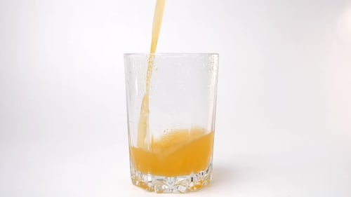 Pouring Orange Juice into a Glass on White