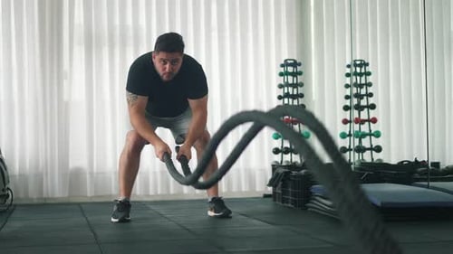 Männertraining im Fitnessstudio mit Battle Ropes Gym Workout in Zeitlupe