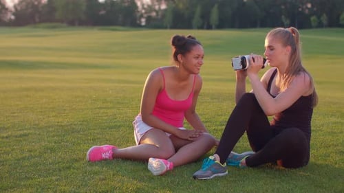 Women in park share virtual reality headset