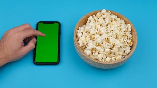 Hand Using Phone With Green Screen And Popcorn