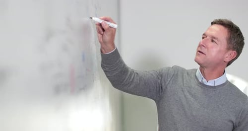 Man Writes on Whiteboard in Office Environment