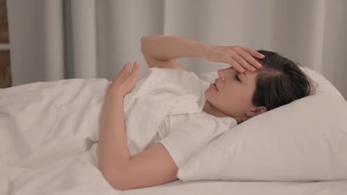 Side View of Young Indian Woman with Headache Lying in Bed