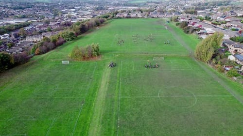 Drone video footage of extensive playing fields situated on the summit of a hill. Showing football p