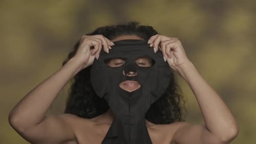 Woman Applying Black Facial Mask for Skincare