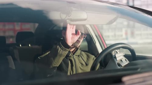 Man Adjusts Sun Visor in Car in City