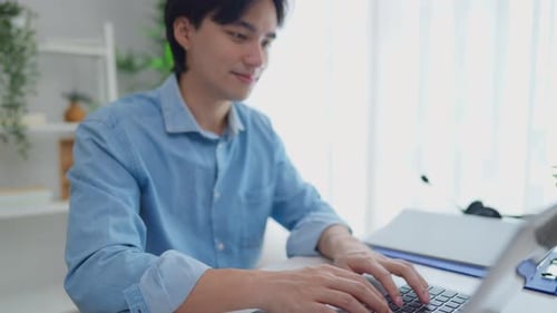 Smiling Man Working on Laptop at Bright Desk