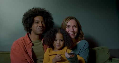 Family Togetherness on Green Couch with Child Holding Remote