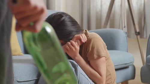 Upset Woman on Floor with Bottle in Foreground