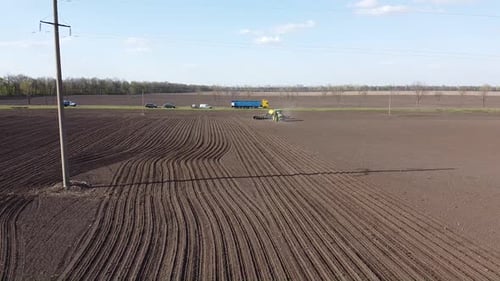 Tracteur avec semoir jaune travaillant sur le terrain en Ukraine OA Lexa