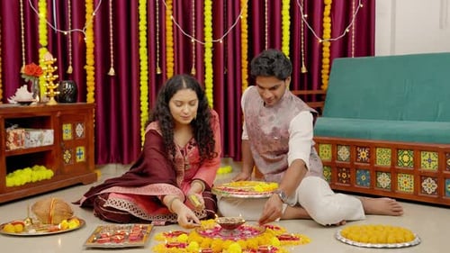 Adults Prepare Festive Candle and Floral Display Indoors
