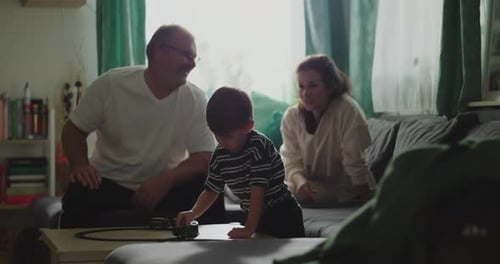 Family Relaxing Indoors Watching Child Play with Toy