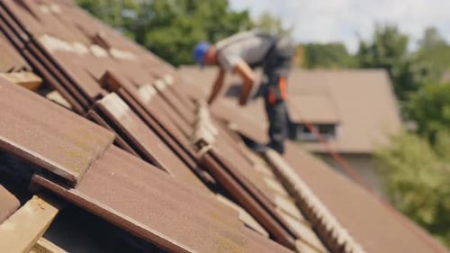 Roofer Working on Tiled Roof on Sunny Day