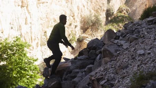 Silhouette of a Hiker Man Climbing Onto a Rocky Hill A Man Hiking Up a Huge Mountain Field of Rock