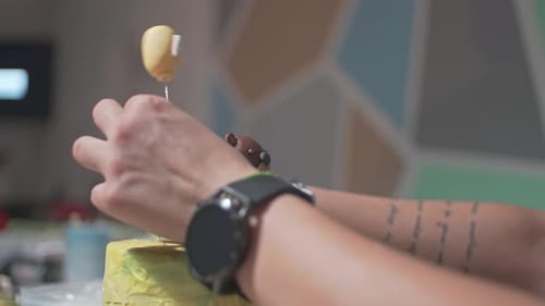 Close up on caucasian woman hands, decorating a cake with a bear and balloon made of sugar paste fon
