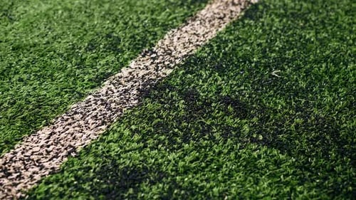 close-up of a hand running across a football synthetic grass with a rubberized texture