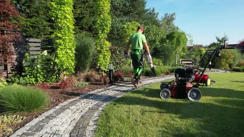 Caucasian Gardener Blowing Dirt and Leafs From Garden Cobble Paths