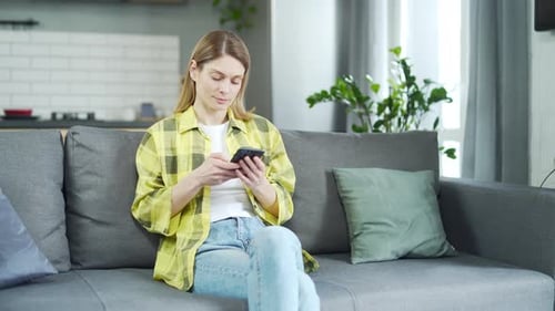 Woman Relaxing on Couch Using Smartphone