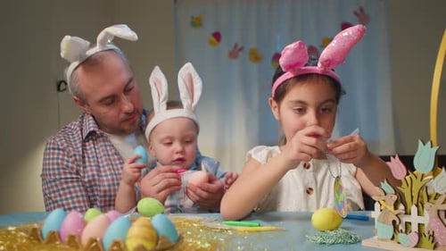 Father and Children Color Easter Eggs at the Table Preparing for the Holidays
