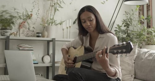 Woman Plays Guitar at Home