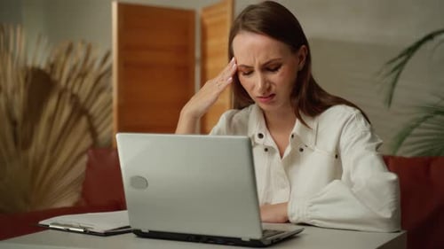 A Woman Touches Her Temples Feeling Stressed A Girl in a Home Office Tired of Work Feels a Headache