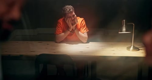 Young Adult with Handcuffs Sits in Dark Room