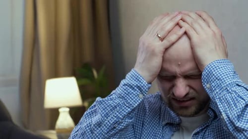 Distressed Man Holding Head in Hands Indoors