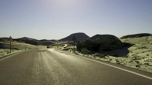 Bright Sun Illuminating Vast Desert Roadway with Dramatic Shadows and Wide Sky