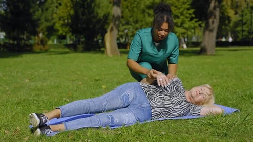 Woman Assists Senior Woman with Exercises in Park