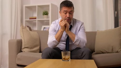 Man With Head in Hands Drinks Whiskey