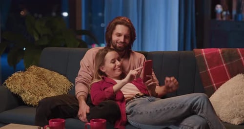 Relaxing Couple Looking at Phone on Couch at Home