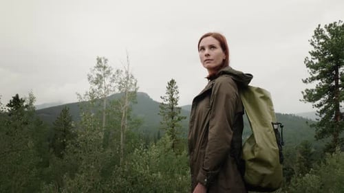 Auburn-haired Woman with Backpack Looks at Mountain View