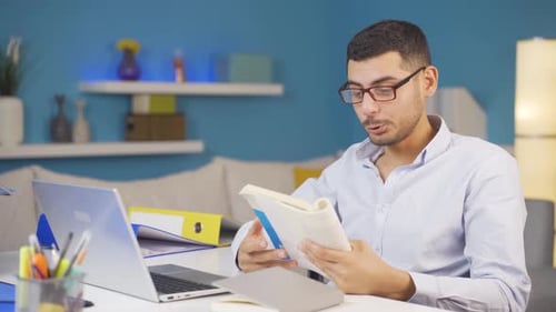 Home office worker man reading a book.