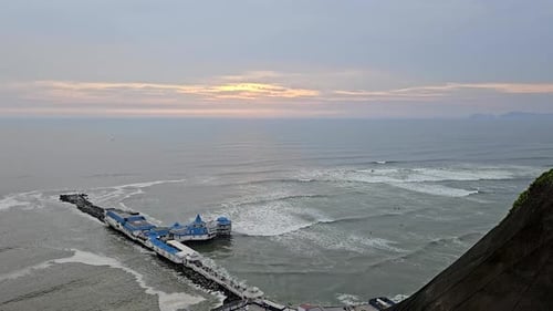 Muelle y surfistas sentados en olas ondulantes durante una puesta de sol en el distrito de Miraflores de Lima, Perú.
Lima