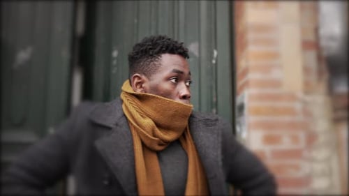 Man Wearing Scarf and Coat Walking on City Street