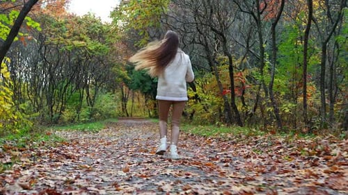 Outdoor playful young lady in autumn park. Stylish beautiful female lifestyle.