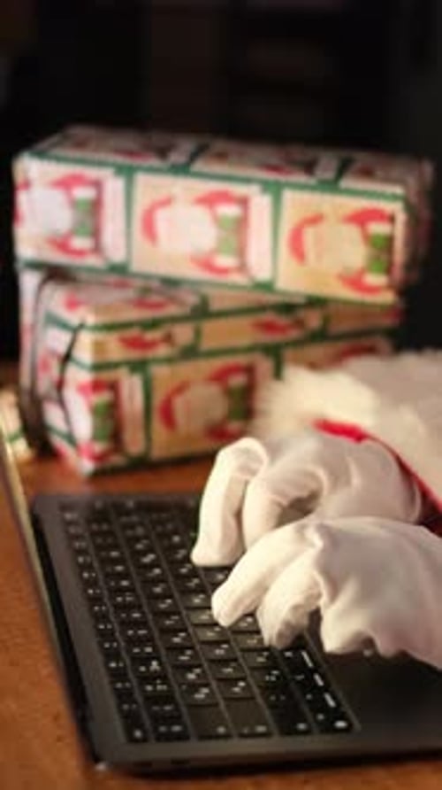 Santa Claus Typing on Laptop Keyboard with Christmas Presents
