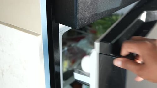 Opening a Modern Refrigerator Door in a Home Kitchen