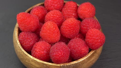 Ripe raspberries close up rotate in a wooden bowl. Juicy fresh raspberry berry is healthy