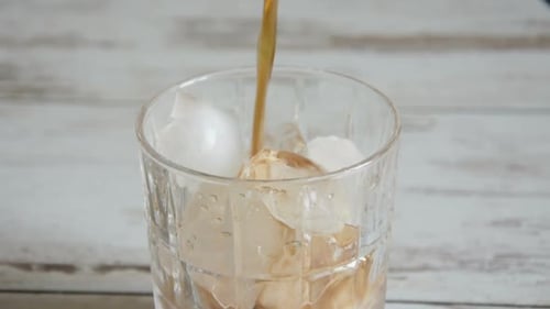 Fizzy Brown Drink Being Poured Over Ice Cubes