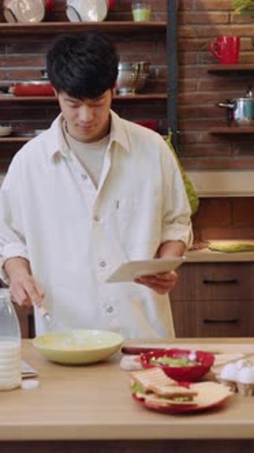 Young Man Cooking Using Tablet in Kitchen
