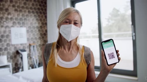 Woman holds digital COVID pass in hospital room