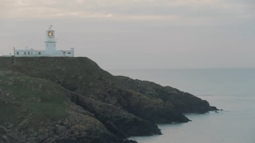 Blick auf den Leuchtturm an bewölktem Abend. Schwenken Sie hinüber zu und hören Sie auf. Leuchtturm von Strumble Head.