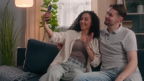 Happy Couple Taking Selfie on Sofa Indoors