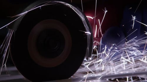 Close-up: Handheld cut-off disc tool makes sparks while cutting steel