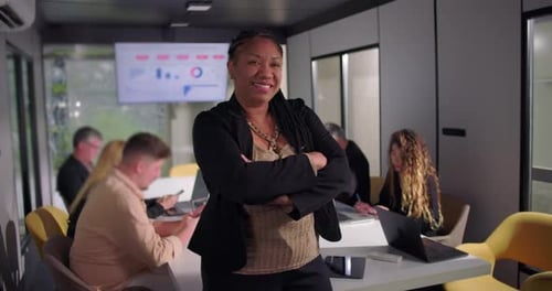 Smiling African American businesswoman standing with arms crossed in office, confident leadership