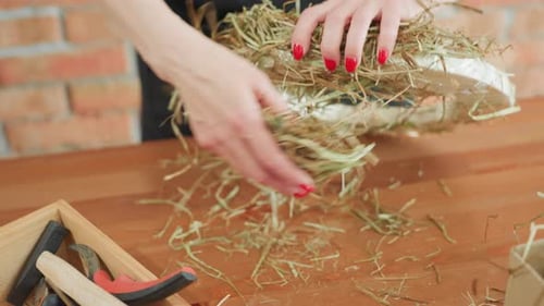 Florist Arranges Dried Grass Onto Circular Base Using Hands with Red Nails